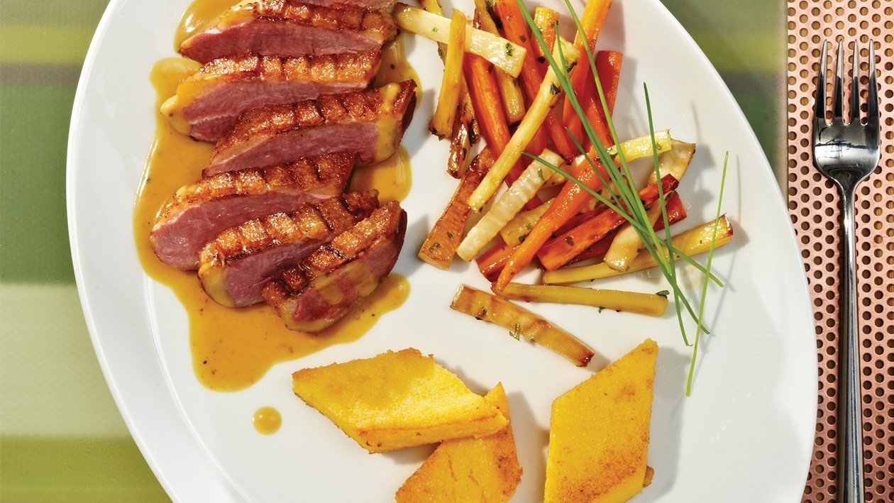 Entenbrust an pfeffriger Curry-Blutorangen-Sauce, glaciertem Wurzelgemüse und Polentaplätzchen