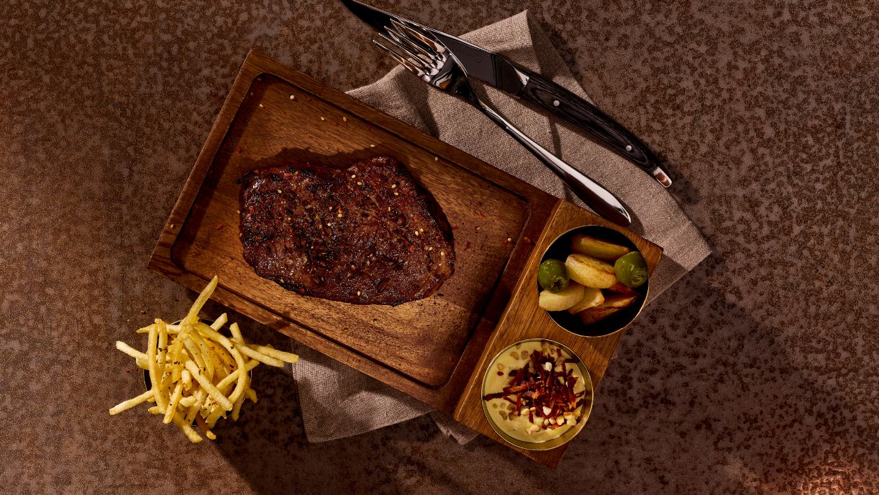 Rosé gegrilltes Entrecote vom Rind, Haselnuss-Speck-Bearnaise, Kohlrabi-Oliven Gemüse und Strohkartoffeln –  